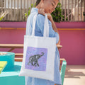 Woman holding a tote bag with a design of an elephant on a colorful background