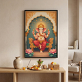 A framed vertical art print of Lord Ganesha seated on a throne, displayed on a beige wall above a wooden altar with decorative items. The print features Ganesha in pink and gold robes against a teal and gold arch background.