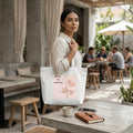 Woman holding a tote bag with a motivational quote in an outdoor setting.