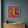 A framed colorful pop-art print of Ganesha hanging on a dark teal-gray wall above a light wood console table with a small succulent and books.