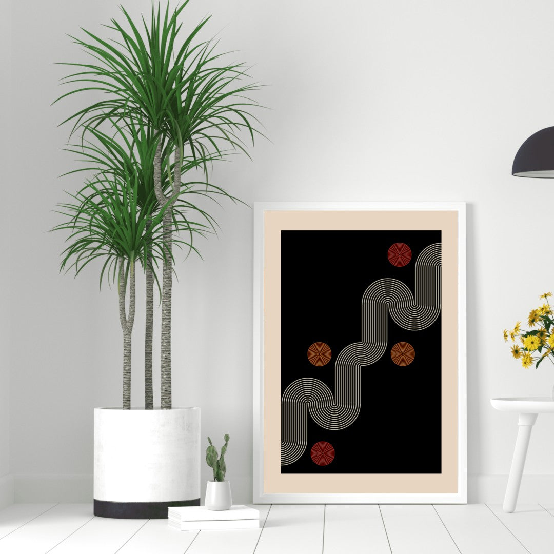 Framed abstract art print on a white wall with a plant and small table in the foreground.
