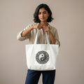 Woman holding a white tote bag with a mandala design on a beige background